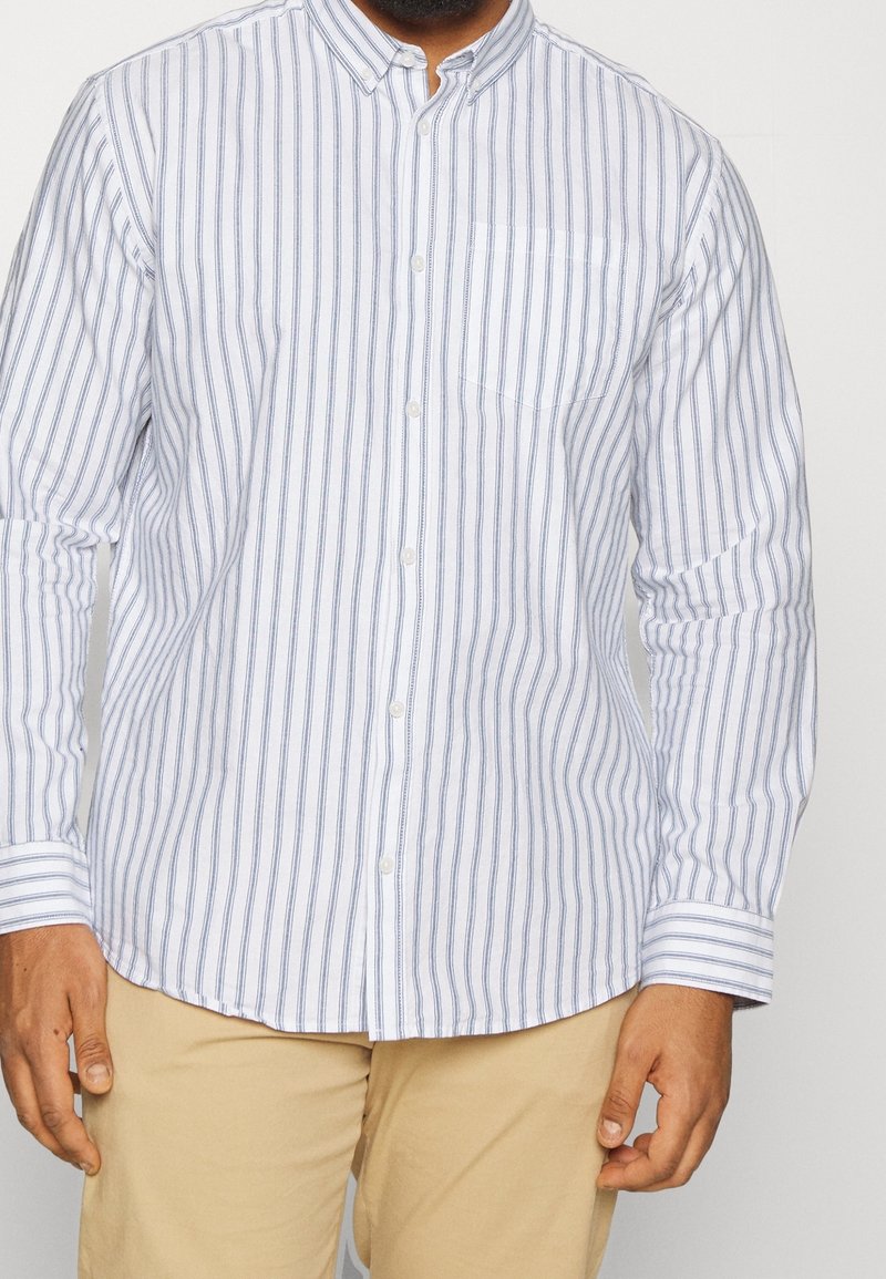 Pitkähihainen nappipaita vaaleansinisin ja valkoisin pystyraitoin, jossa on klassinen kaulus ja rintatasku. Puuvillakangasta.