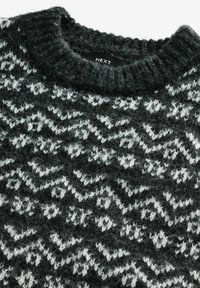 Pull en tricot avec un motif en zigzag noir et blanc, doté d'un col rond côtelé et d'un tissu doux et texturé. Étiquette de la marque visible.