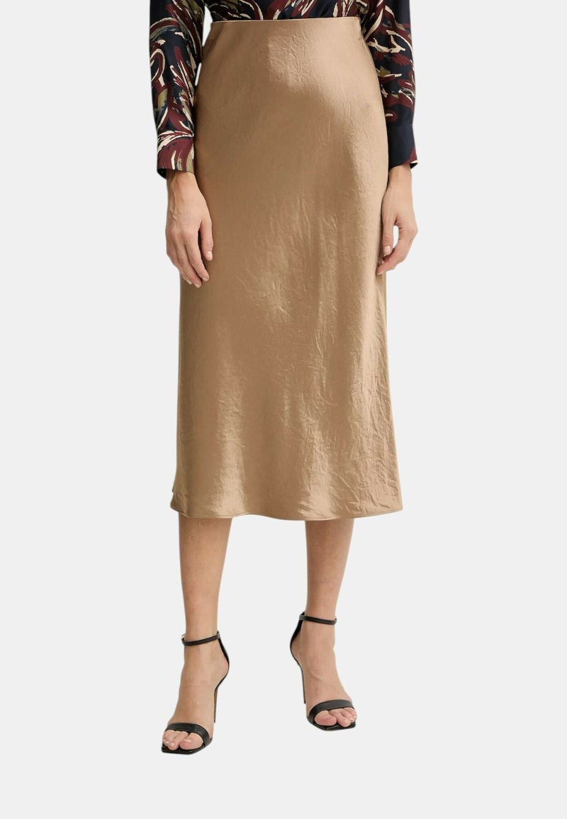 Gonna beige di media lunghezza in tessuto morbido e arricciato. Presenta una silhouette dritta e una texture liscia, abbinata a sandali neri con tacco.