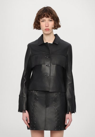 Veste en cuir noir avec un col, un devant à boutons et des détails à franges. Associée à une jupe en cuir noir assortie avec des accents à laçage.