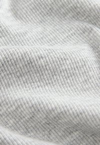 Hellgrauer, gerippter Stoff mit weicher Textur und vertikalen Linien. Das Material wirkt wie Baumwolle oder eine Baumwollmischung.