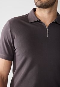 Short-sleeved polo shirt in dark gray with a textured finish, featuring a short zipper and classic collar design.