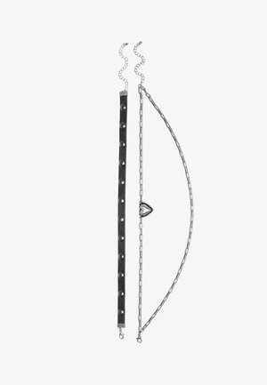 Drei geschichtete Halsketten, die ein schwarzes Lederband mit silbernen Nieten, eine silberne Kabelkette und einen herzförmigen Anhänger zeigen.