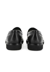 Scarpe in pelle nera con una finitura liscia, punta rotonda e suola in gomma bassa. Ci sono dettagli di cucitura minimi sulle tomaie.