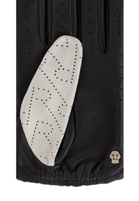 Guante de cuero negro que presenta un parche de cuero blanco con un patrón de zigzag perforado. Incluye muñequera fruncida y acento de logo metálico.