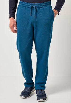 Teal bomulds-sweatpants med elastisk talje og justerbar snøre. Side pockets og en afslappet pasform. Sammen med mørke træningssko.