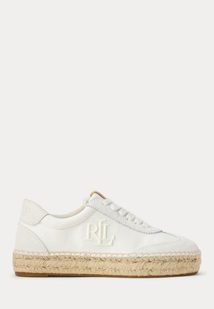 Basket blanche en toile à lacets, avec un monogramme brodé et une épaisse semelle d’espadrille en jute naturel, présentée de profil.