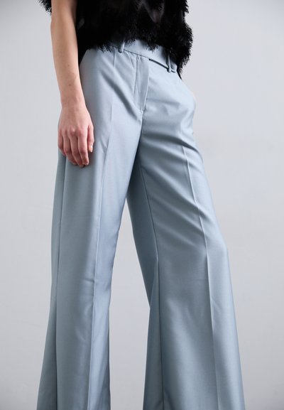 Jasnoniebieskie spodnie o szerokich nogawkach, wykonane z gładkiego materiału. Posiadają dopasowany krój, kieszenie z przodu oraz subtelne zagniecenia wzdłuż nogawek.