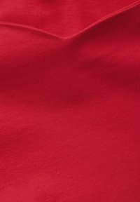 Roter Baumwollstoff mit glatter Textur, der subtile Falten und Farbvariationen zeigt, ohne Muster oder Verzierungen.