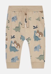 Pantaloni beige per bambini con vita elasticizzata e cordoncino, con motivi di dinosauri e palme in colori blu, verde e marrone.