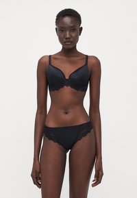 Black lace-trimmed bra with molded cups and adjustable straps, paired with matching lace-accented black briefs. Smooth texture.