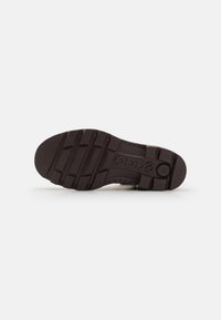 Suola di scarpa in gomma nera con un motivo di presa testurizzato, caratterizzata da un logo in rilievo e scanalature flessibili per una migliore trazione e comfort.