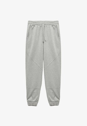 Szare dresy wykonane z miękkiego materiału, z elastycznym pasem, sznurkiem do regulacji i ściągaczami na końcach nogawek. Zawierają boczne kieszenie.