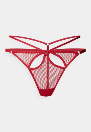 String en maille rouge avec un design à dos ouvert, présentant des bretelles croisées et une découpe décorative au centre. Matériau doux et texturé.