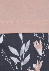 Helles rosa Oberteil mit glatter Textur und kurzen Ärmeln, kombiniert mit einer marineblauen Unterhose, die weiße Blumenmuster und Details aufweist.