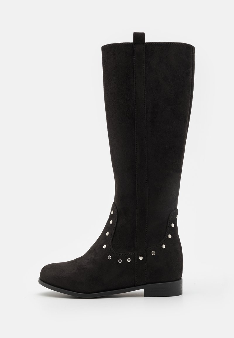 Botas negras hasta la rodilla hechas de ante, con una textura suave, puntera redondeada y tachuelas metálicas a lo largo del costado. Tacón plano con una lengüeta.