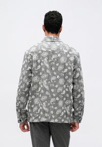 Hallgray kangast särk, millel on valged paisley ja lillemustrid, pikkade varrukatega ja nööbiga mansetiga, disainitud kraega kaelusega.