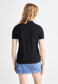 Černé polo tričko s krátkým rukávem, směs bavlny, slim fit, s sklopeným límečkem, kombinované se světle modrou džínovou sukní.