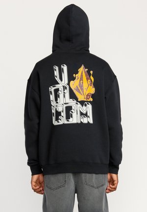 Black hoodie featuring bold white lettering "VOLCOM" and a yellow flame-shaped graphic on the back. Material appears soft, with a relaxed fit.