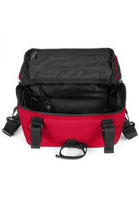 Borsa rettangolare rossa con interno nero, dotata di chiusura a zip, spallacci regolabili e maniglia superiore per il trasporto.