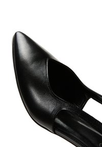 Zapato de tacón alto de cuero negro con punta afilada y diseño de corte lateral, que presenta una textura suave y una silueta elegante.