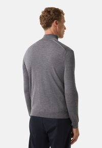 Grauer Pullover mit hohem Kragen, aus weichem Strickstoff gefertigt. Er verfügt über lange Ärmel, eine enganliegende Silhouette sowie gerippte Bündchen und Saum.