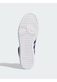 Weiße Gummisohle mit Musterprofil und kreisförmigem Detail, mit marineblauen Akzenten an den Seiten und Branding.