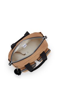 Brun Kipling taske med sorte håndtag, to frontlynlåse lommer, åben hovedrum, der viser beige inderside og nøgleclip, sort pom-pom charme vedhæftet.