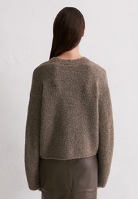 Brązowy sweter dzianinowy z długimi rękawami, okrągłym dekoltem i teksturowanym, puszystym wykończeniem. Projekt jest luźny i skrócony w talii.