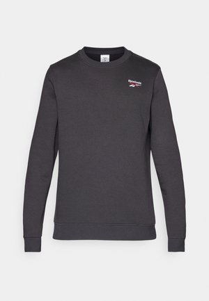 Tmavošedý sveter z jemnej bavlnenej zmesi. Má okrúhly výstrih, dlhé rukávy a malé červené logo Reebok na hrudi.
