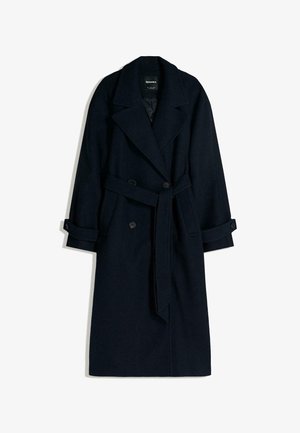Cappotto lungo in lana navy scuro con chiusura doppiopetto, colletto ad alette oversize e cintura da annodare. Presenta maniche con risvolto e una forma strutturata.