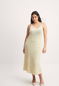 Knit midi-mekko vaaleankeltaisena, jossa on ribbaustekstuuri ja ohuet olkaimet. Mukana muotoon puristava siluetti ja koristeelliset kabelikuvioinnit.