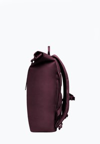 Zaino bordeaux con design a roll-top, tessuto testurizzato, spallacci imbottiti e cerniera laterale. Presenta inserti in rete e fibbie regolabili.
