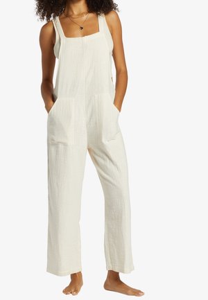 Kremowy, teksturowany model z szerokimi ramiączkami, dwoma przednimi kieszeniami oraz luźnym, swobodnym krojem. Lekka, oddychająca tkanina.