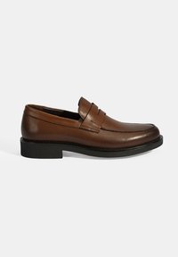 Bruine leren loafers met een zachte afwerking, gestikte details en een zwarte rubberen zool. Heeft een band aan de voorkant met twee snedes.