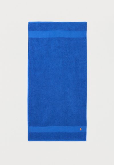 Φωτεινή μπλε ορθογώνια πετσέτα με απλή περίμετρο και μικρό πορτοκαλί κεντημένο λογότυπο κοντά σε μια γωνία.