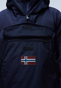 Námořnická modrá, voděodolná bunda s kapsou na zip a suchým zipem, na kterém je zobrazen norský flag. Hladký, lehký materiál.