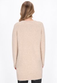 Beige Langarm-Pullover aus weichem, strukturiertem Stoff. Mit einem runden Ausschnitt und gerippten Säumen an den Ärmelenden und am Saum.