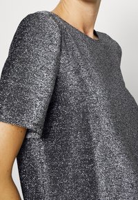 Grijze kortemouwtopp gemaakt van glanzende stof, met een ronde halslijn en een rechte snit, met een zachte textuur en reflecterend oppervlak.