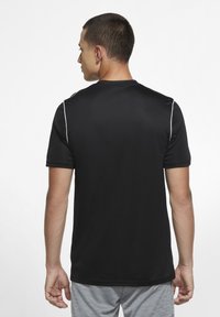 Camiseta atlética negra de manga corta con ribete blanco a lo largo de los hombros. Confeccionada en una tela suave y ligera, diseñada para la comodidad y la flexibilidad.