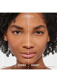 Comparaison avant-après d'un visage avec des cheveux bouclés ; le côté gauche présente une peau naturelle, tandis que le côté droit semble amélioré avec un teint lisse.