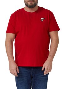 Rotes Baumwoll-T-Shirt mit kurzen Ärmeln, rundem Ausschnitt und einem kleinen Snoopy-Motiv auf der linken Brust. Kombiniert mit blauen Jeans.