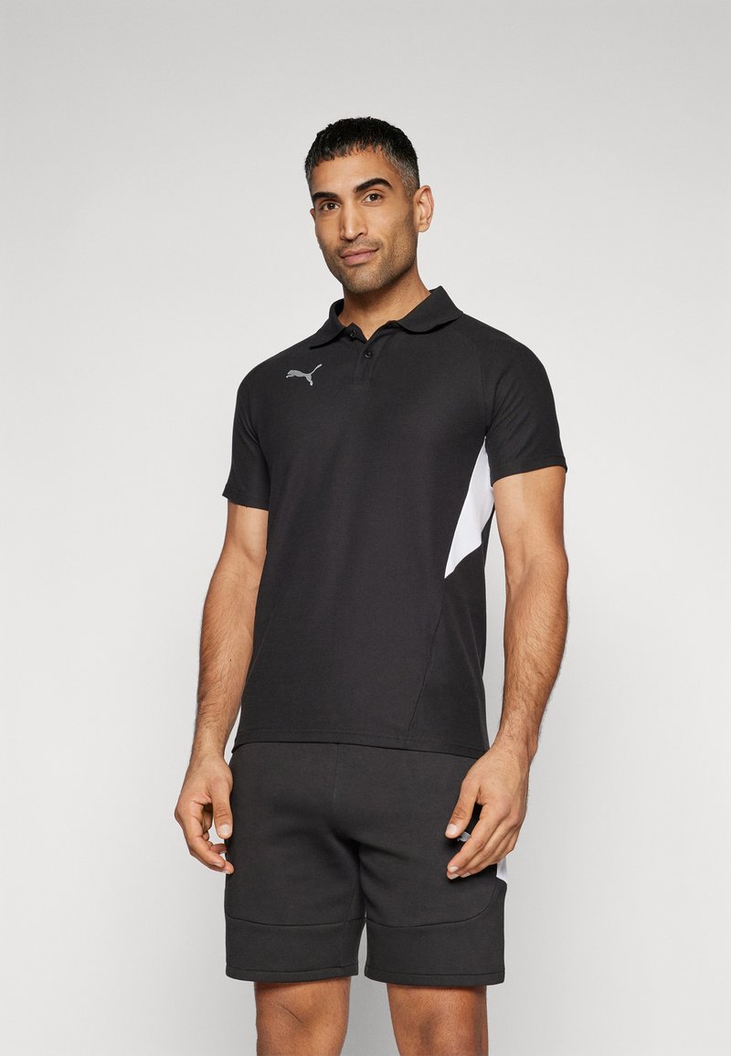 Polo noir avec un panneau latéral blanc, fabriqué en tissu lisse. Dispose d'un col classique et de manches courtes, avec un logo sur la poitrine.
