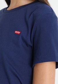 Dunkelblaues Baumwoll-T-Shirt mit klassischem Rundhalsausschnitt, kurzen Ärmeln und einem kleinen roten Levi's-Logo-Patch auf der Brust.