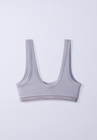 Ανοιχτό γκρι αθλητικό σουτιέν Calvin Klein με φαρδιές τιράντες και ελαστική ταινία με λογότυπο, τοποθετημένο επίπεδα πάνω σε λευκό φόντο.
