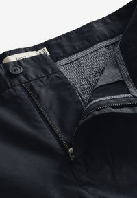 Námořnické modré kalhoty se zipem a knoflíkovým zapínáním. Podšity geometrickým vzorovaným materiálem a s detailem šití kolem pasu.