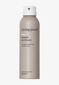 Grå aerosolbeholder med en hvit spraydyse, merket "Living proof frizz instant de-frizzer" i svart tekst, 208 mL størrelse, glatt metallisk overflate.