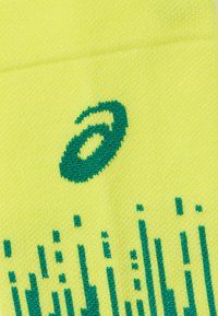 Sosete galbene strălucitoare cu un model tricotat texturat, având accente grafice verzi, inclusiv un logo și modele de linii verticale.