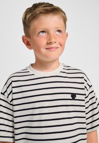 Randig T-shirt i cream och marinblått. Mjukt bomullsmaterial, rund halsringning, ledig passform. Liten broderad logga på bröstet. Kortärmad.