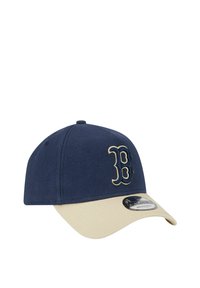 Navy blue cap with a beige brim, featuring an embroidered letter "B" in gold. Made of textured fabric with an adjustable strap.